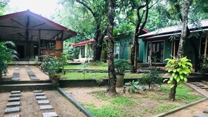 A courtyard with a covered seating area, a pathway, and a small garden with trees and plants.