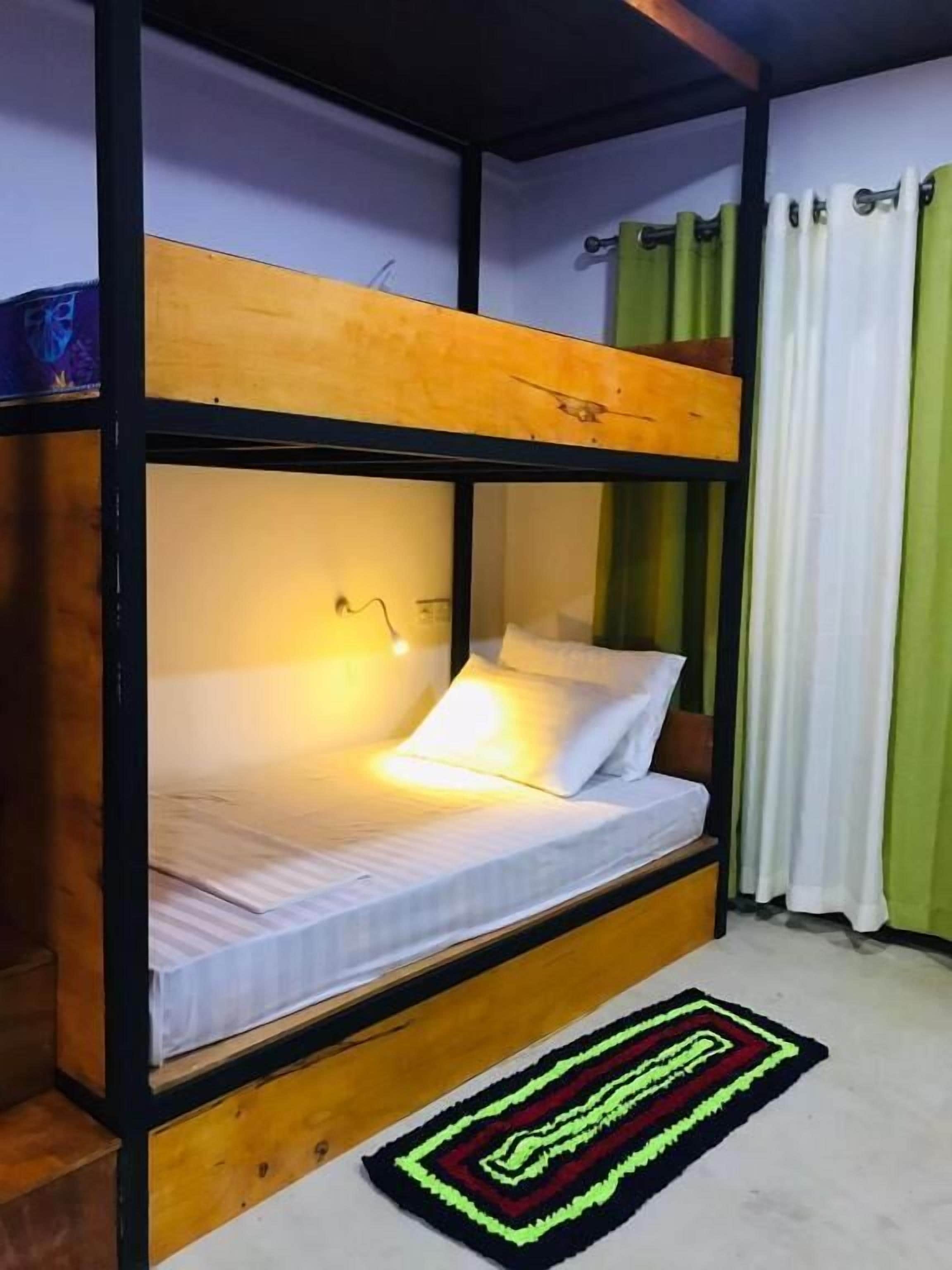 Una cama litera con estructura de madera, colchón blanco y una sola almohada.