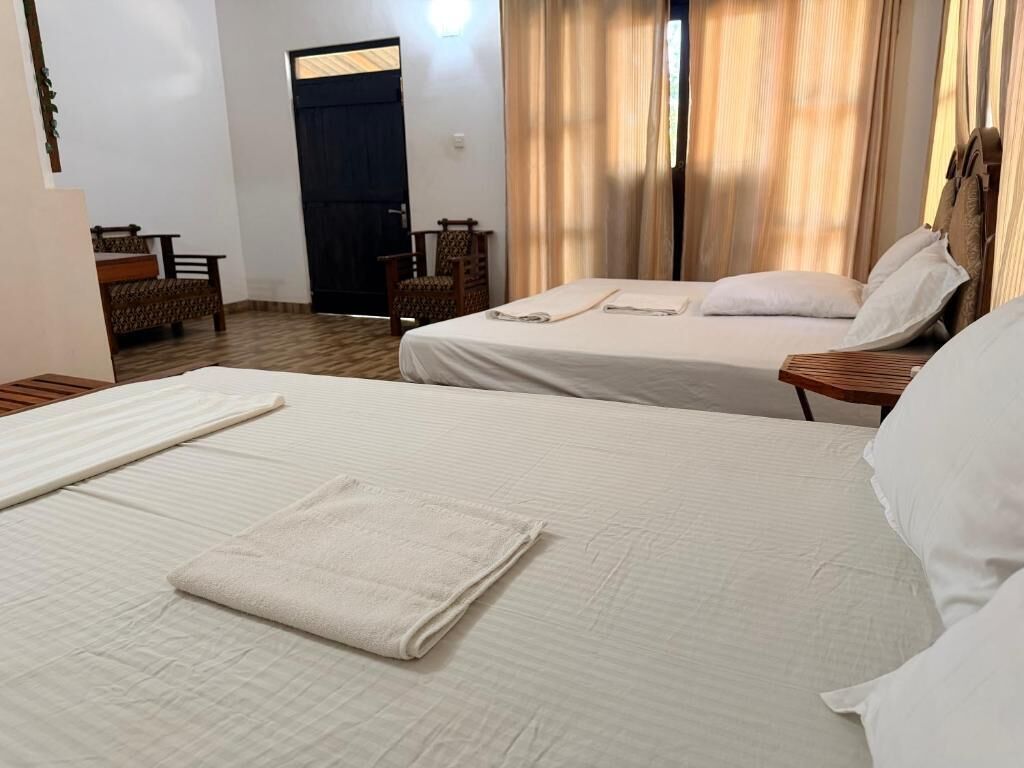 Ein Hotelzimmer mit zwei Betten, Holzboden, Schreibtisch und Stuhl.