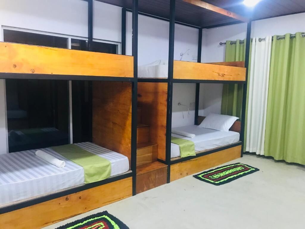 A room with bunk beds, a window, a green curtain, and a patterned rug.