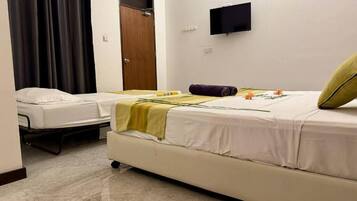 A room with two beds, a flat-screen TV, a wooden door, and a curtain.
