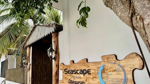 Un panneau en bois portant l’inscription « Seascape Retreats Dhigurah » et un motif circulaire bleu.