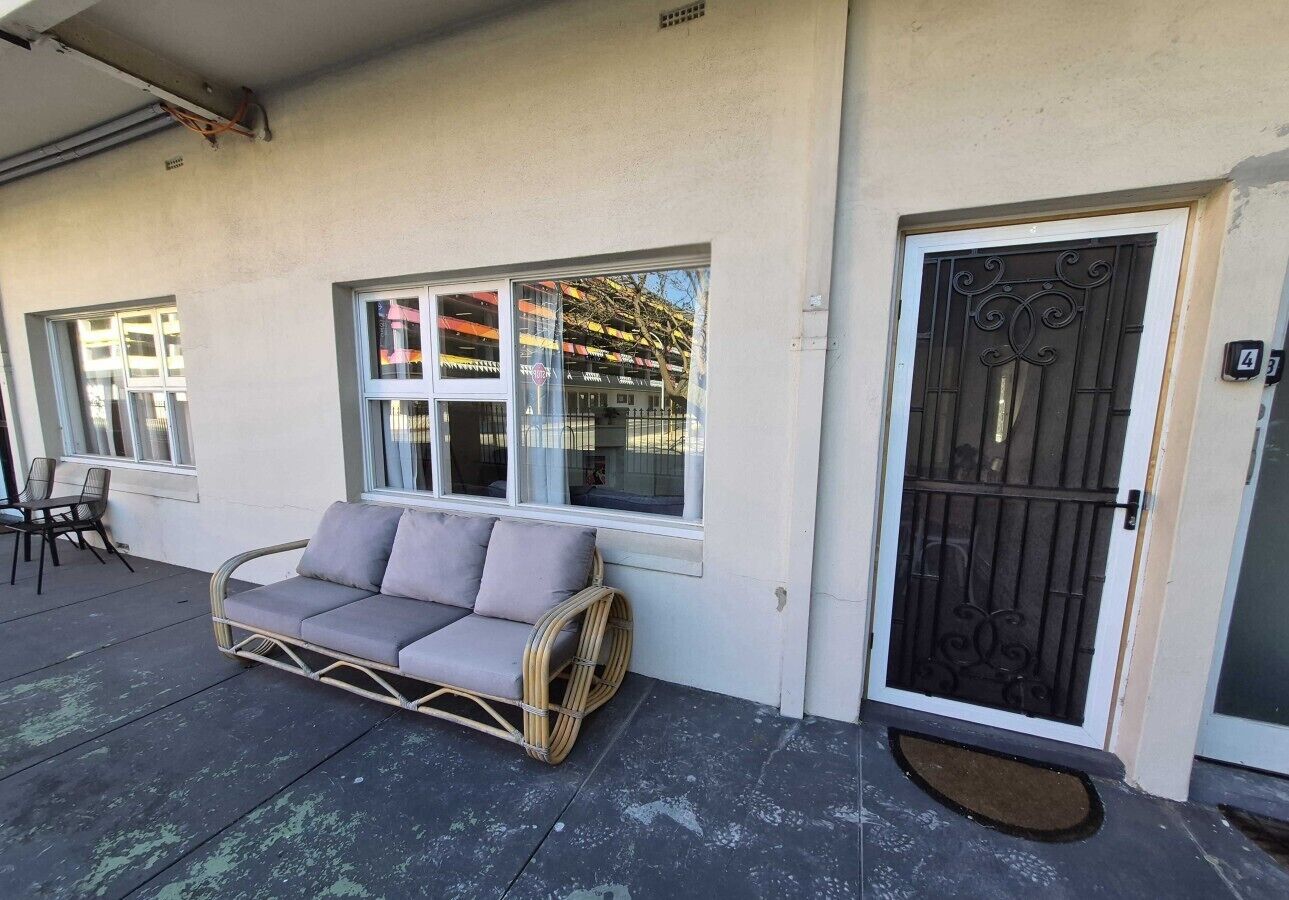 A room with a sofa, a door with a metal gate, and a window with a view of a building.