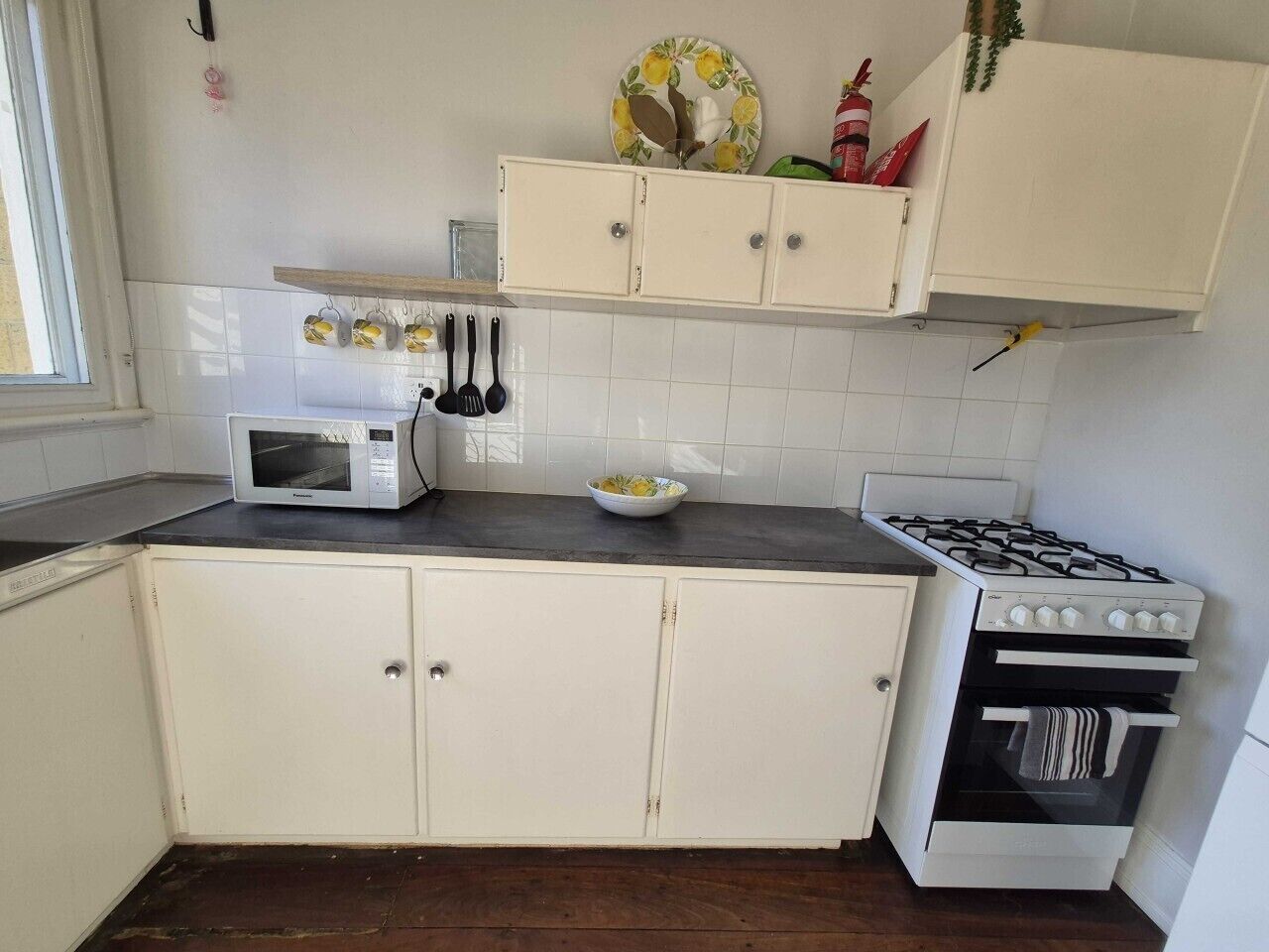 A kitchen with white cabinets, a microwave, a gas stove, and a small oven.