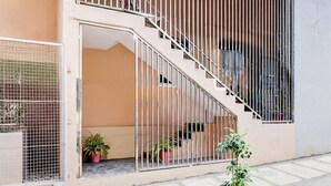 A modern building with a staircase leading to a balcony, potted plants, and a metal gate. - Saver Single Bangalore Inn (Bengaluru)