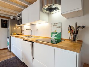A modern kitchen with white cabinets, a wooden countertop, a sink, and a backsplash with a warning sign. - NoLo Garden Loft by Interhome (Milan)