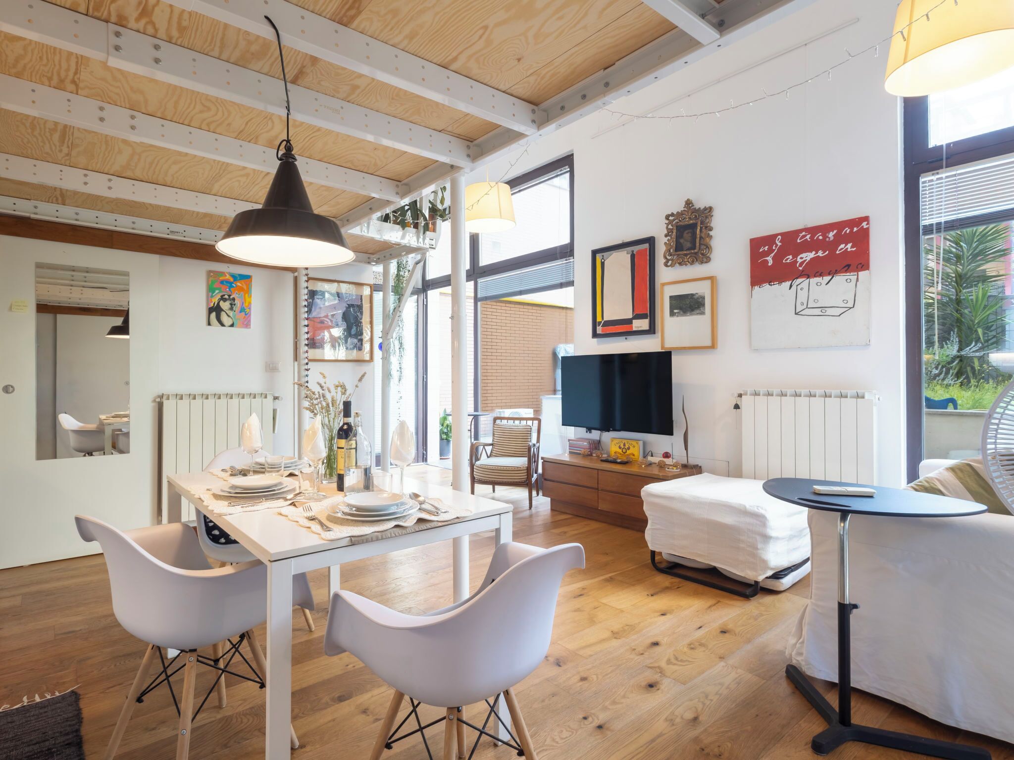 Un intérieur moderne avec une table à manger, des chaises blanches, un canapé et un téléviseur.