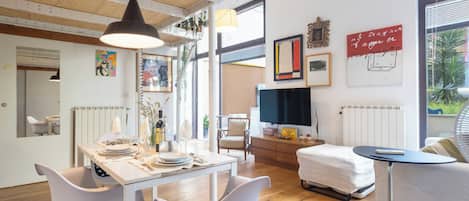 Un intérieur moderne avec une table à manger, des chaises blanches, un canapé et un téléviseur.