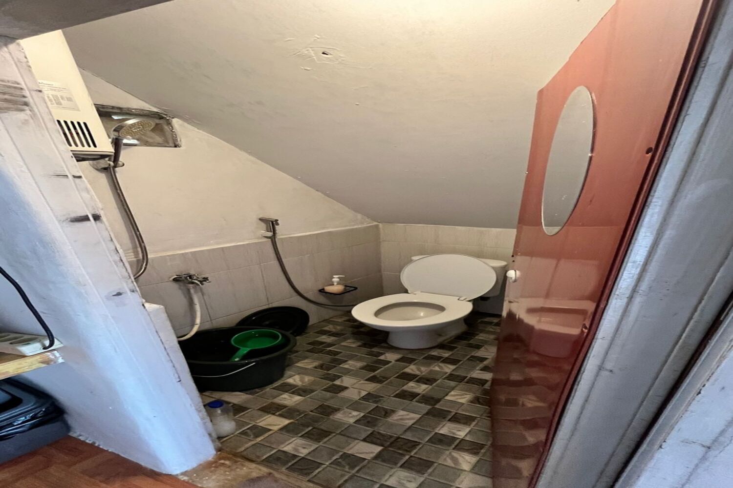 Une petite salle de bain étroite, équipée de toilettes, d’une douche et d’un lavabo.