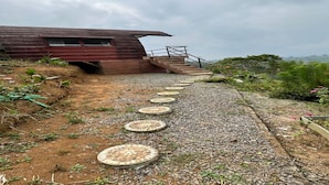 A pathway leading to a building with a sloped roof and a staircase.