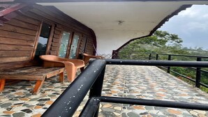 A covered outdoor area with a tiled floor, wooden benches, and a railing.