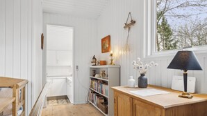 Une pièce avec un bureau en bois, une bibliothèque et une fenêtre donnant sur des arbres.