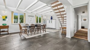 A spacious room with a dining area, a staircase, and a view of the outdoors. - Lovely cottage with amazing sea view (Assens)