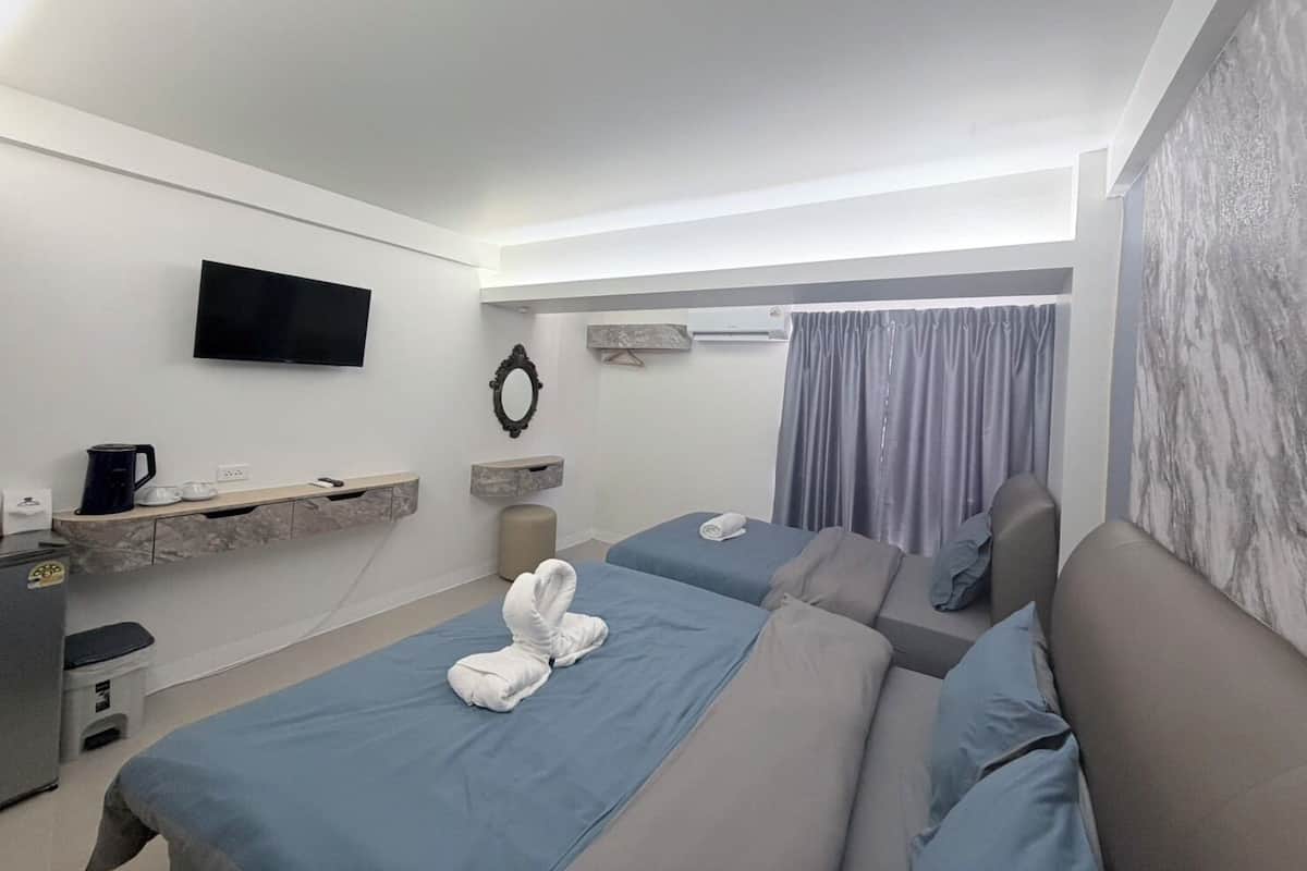 Ein modernes Hotelzimmer mit zwei Betten, einem Fernseher, einer Kaffeemaschine und einem kleinen Schreibtisch.