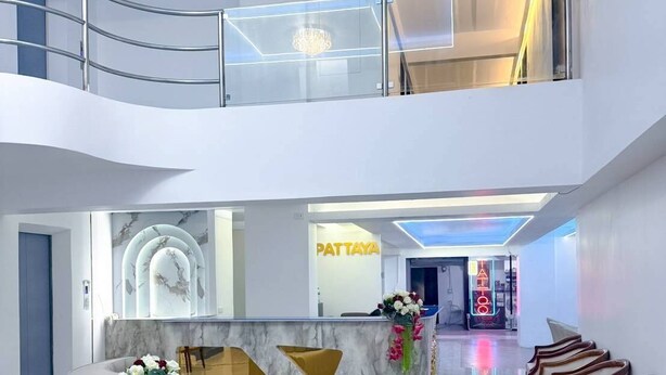Un vestíbulo amplio con mostrador de recepción, zona de estar y escalera.