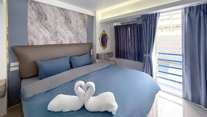 Habitación de hotel moderna con una cama grande, una pared de mármol, vistas por la ventana y un espejo decorativo.