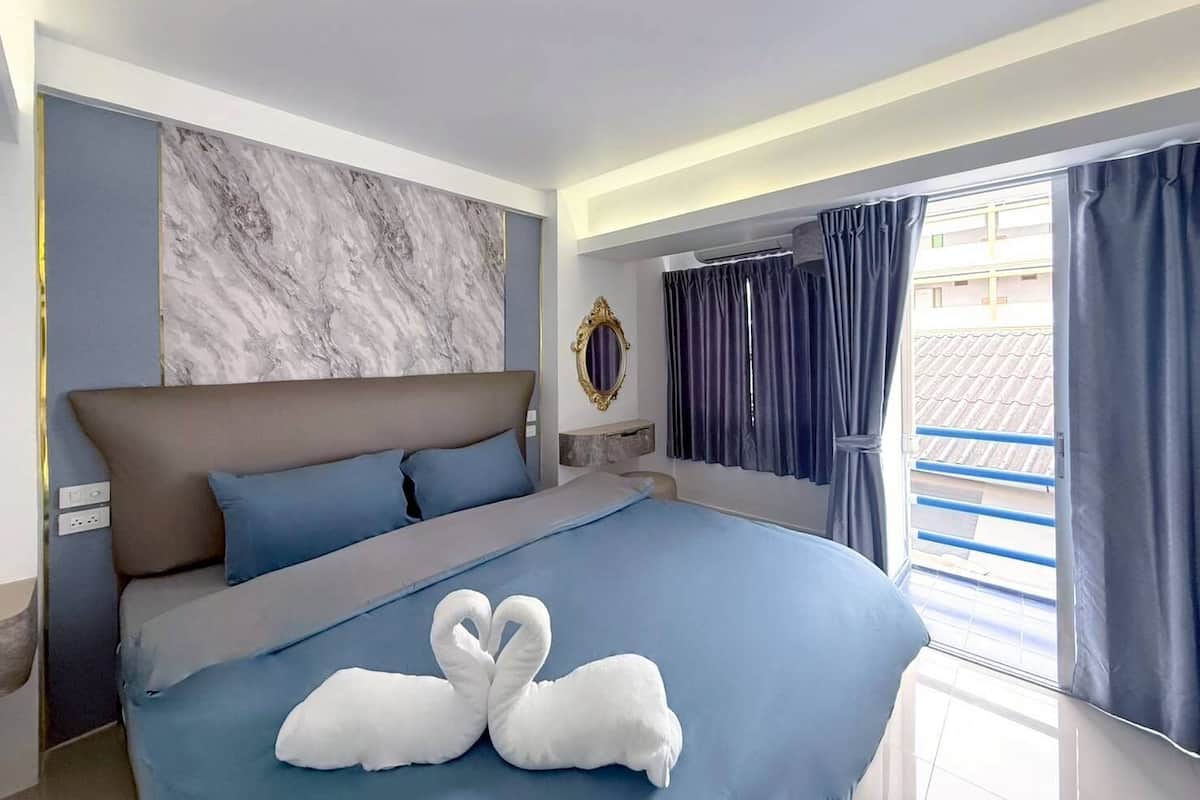 Ein modernes Hotelzimmer mit einem großen Bett, einer Marmorwand, Blick durch das Fenster und einem dekorativen Spiegel.