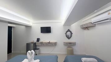 Una habitación de hotel moderna con dos camas, un televisor, un tocador de mármol y un equipo de aire acondicionado.
