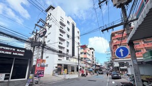 Una calle con edificios, un bar deportivo y un scooter de reparto.
