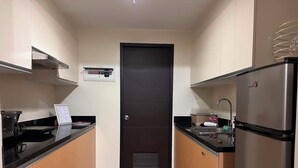 A modern kitchen with a black door, stainless steel appliances, and wooden cabinets.