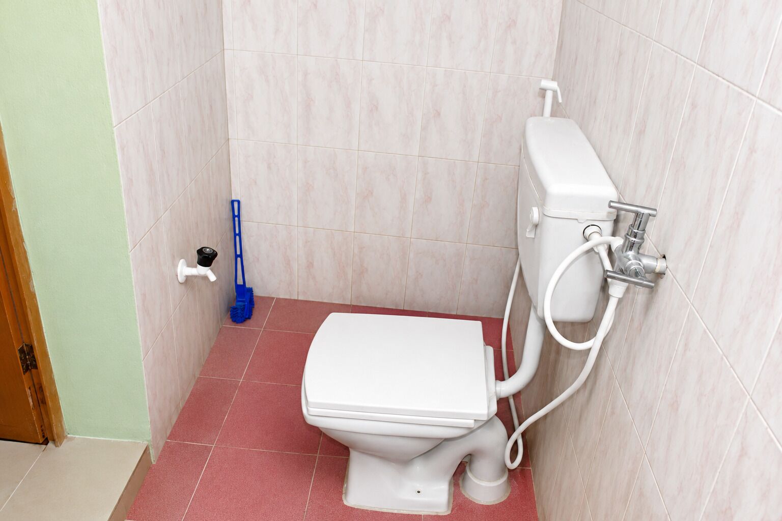 A small bathroom with a toilet, a bidet, and a mop.