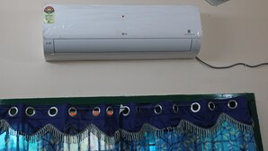 An air conditioner mounted on a wall with a curtain below it. - Sri Arunachala Homestay (Tiruvannamalai)