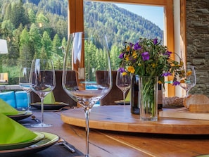 Ein Esstisch mit Weingläsern, einer Blumenvase und Brot.