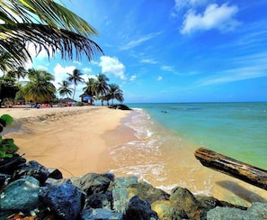 A beach with clear water, palm trees, and a wooden structure. -  Spacious 1 Bedroom apartment in Crown Point AC,hot and cold water and pool. (Crown Point)