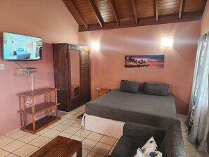 A bedroom with a bed, a TV, a wooden cabinet, and a painting on the wall.