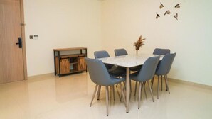 Zona pranzo con tavolo rotondo, sei sedie, un piccolo mobile e decorazioni a forma di uccelli appese al muro.