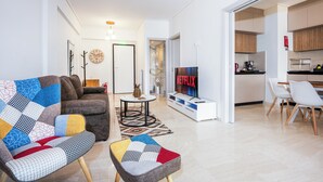 A modern living room with a sofa, a coffee table, and a TV displaying 'NETFLIX'. - Amphitryon Residence | 2BR Apartment in Glyfada (Glifada)