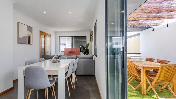 A modern hotel room with a dining area, a glass partition, and a view of the outdoors. - GuestReady-Charming Ponta Delgada Retreat (Ponta Delgada)