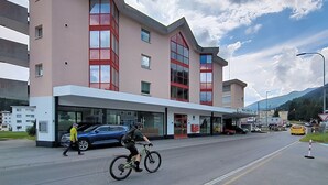 A modern building with a flat roof, large windows, and a pedestrian walkway. - Flüela Lounge by Interhome (Davos)
