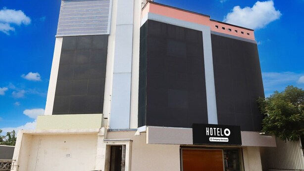 A modern hotel building with a large entrance, a visible signboard, and a clear sky. - Premium Ssm Murugan Rooms (Sriperumbudur)