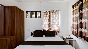 A bedroom with a wooden wardrobe, a bed with white bedding, a nightstand, and a wall-mounted air conditioning unit. - Premium Ssm Murugan Rooms (Sriperumbudur)