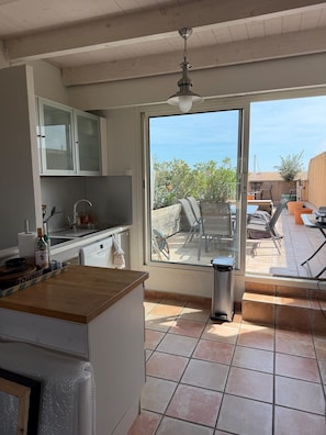 A kitchen with a window leading to an outdoor patio area. - "Le Rooftop Azur" (sleeps 6) Ocean view (Hyères)