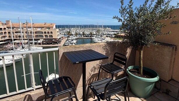 Eine Terrasse mit Tisch und Stühlen mit Blick auf einen Yachthafen und Boote.