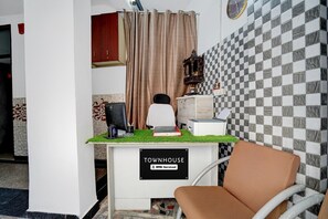 A room with a checkered wall, a desk with a computer, a chair, and a sign that reads 'TOWNHOUSE OYO-Serviced'. - Townhouse Sector 13 Gurgaon (Gurugram)