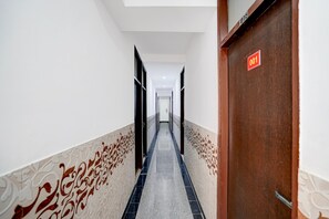 A hotel hallway with patterned walls, a tiled floor, and a door marked with the number 001. - Townhouse Sector 13 Gurgaon (Gurugram)