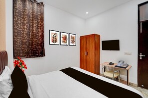 Ein Hotelzimmer mit Bett, Schreibtisch, Kleiderschrank und Fernseher an der Wand.