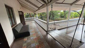 A covered porch with a bench, a swing, and a patterned floor.