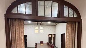 Un salón de conferencias con una larga mesa, sillas y un ventilador de techo.