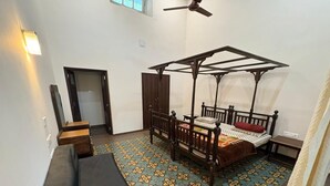 Un dormitorio con cama con dosel, un banco de madera, una mesita pequeña y suelo estampado.