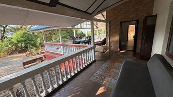 Un espacio al aire libre techado con un banco de madera, una hamaca y vistas del exterior.