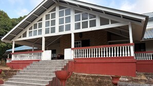 Un edificio con un porche cubierto, una escalera que conduce a la entrada, y una combinación de colores rojo y blanco.