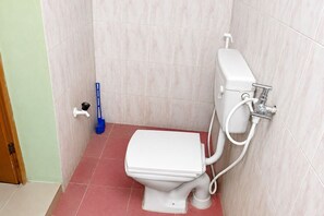 Ein kleines Badezimmer mit Toilette, Bidet und einem Mopp.