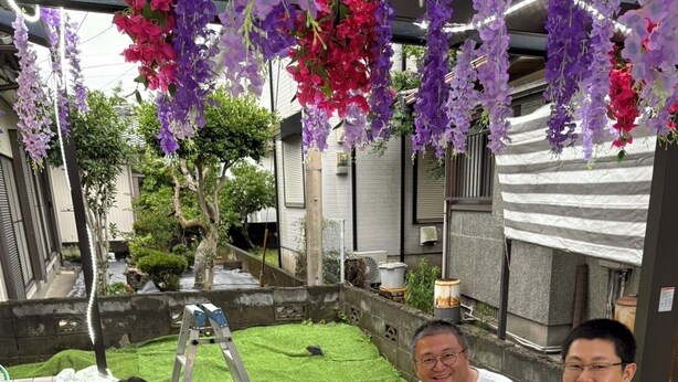 A dining table set outdoors with food, a grill, and hanging flowers. - Non-Smoker Guesthouse MIYAZAKI (Miyazaki)