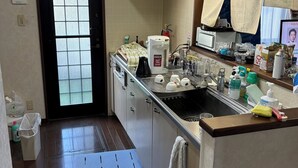 Eine kleine Küche mit Spüle, Herd und einem Fenster mit Vorhängen.