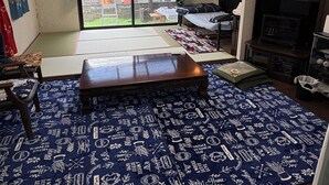 A room with a large sliding glass door leading to a garden, a sofa, a small table, and a cabinet. - Non-Smoker Guesthouse MIYAZAKI (Miyazaki)