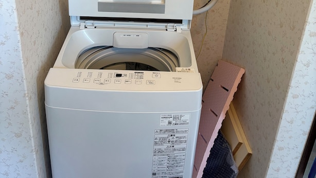 Eine Waschmaschine mit Bedienfeld, einer Steckdose und einem Schild, das eine Waschgebühr von 100 Yen ausweist.